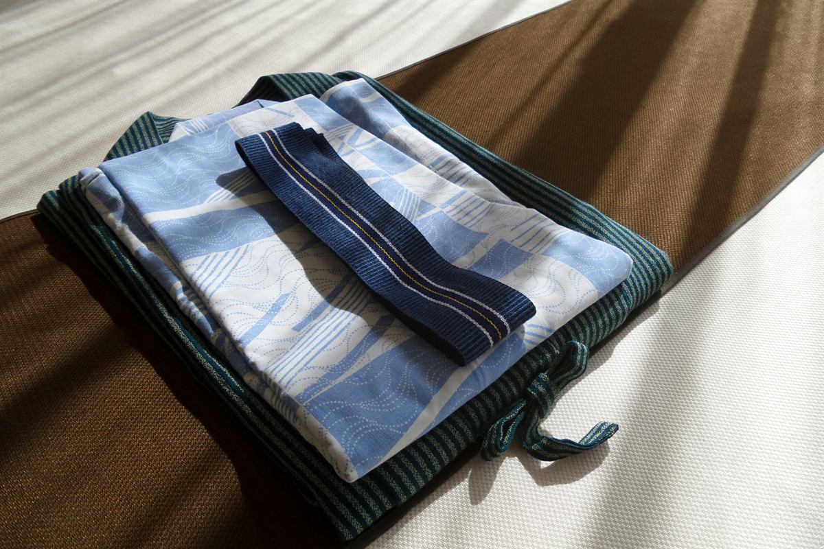 Sleepwear, a sash and a jacket, folded on a hotel bed in Japan.