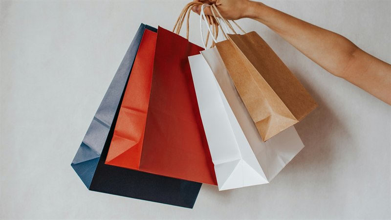 A hand holding several paper shopping bags