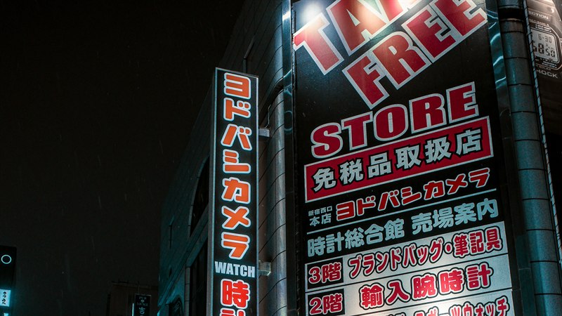 A tax-free store sign lit up above a shop front at night