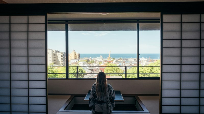 A person in a yukata looking out a window at the Tokyo view